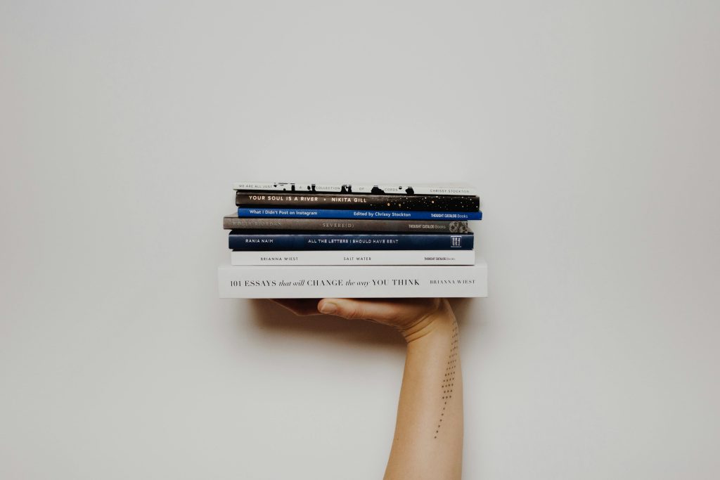 Hand holding a stack of books against a minimal white background, perfect for educational themes.