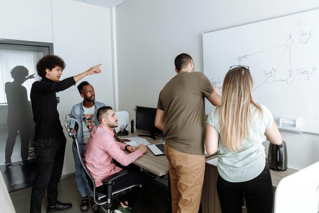 A diverse group of young professionals brainstorming together in a modern office setting.
